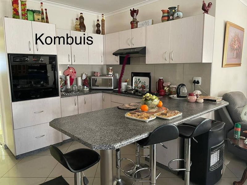Functional kitchen featuring light-toned cabinetry, granite countertops, a breakfast bar, and integrated oven and hob, providing a practical cooking and dining space.