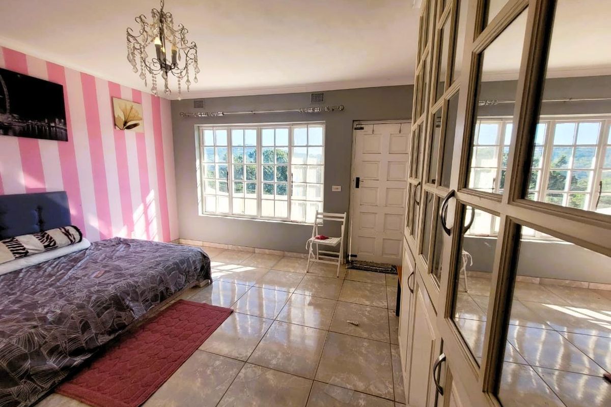Spacious bedroom featuring large windows, tiled flooring, and extensive built-in cabinetry with mirrored doors.