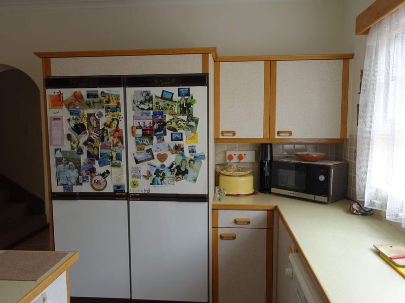 A functional kitchen featuring laminate countertops, tiled backsplash, and traditional built-in cabinetry with a double-door refrigerator.