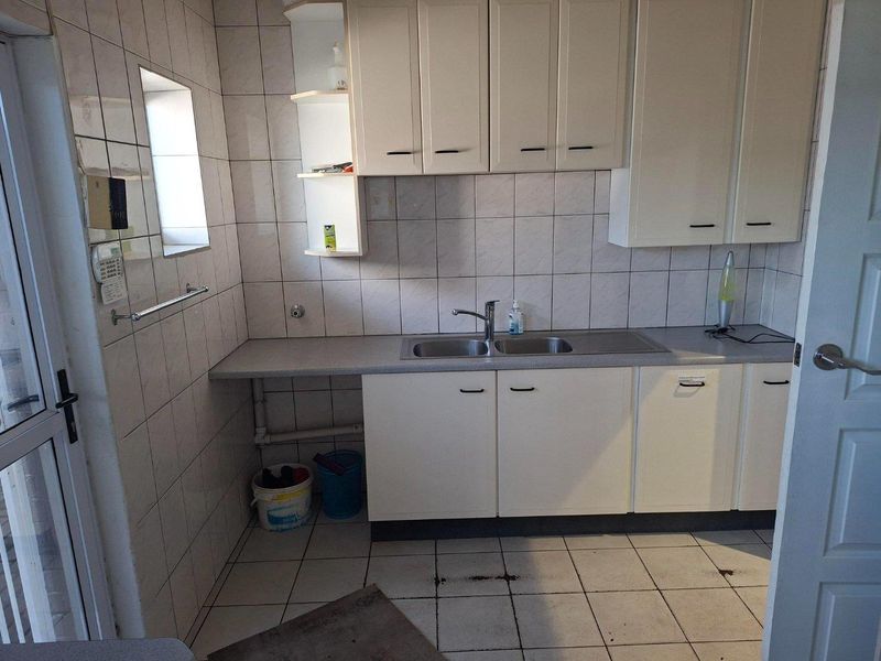 A functional scullery area featuring built-in cabinetry, a stainless steel double sink, and tiled finishes, providing a dedicated space for utility and wash-up tasks.