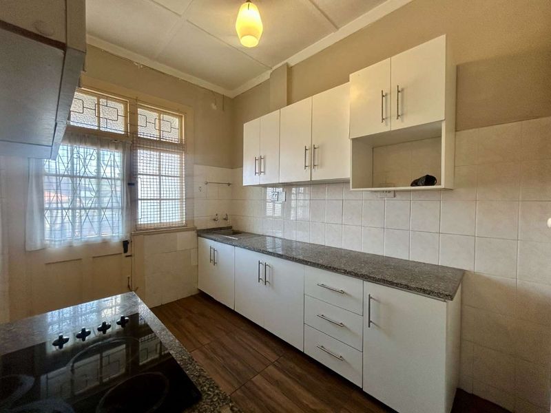 A functional kitchen featuring white built-in cabinetry, granite countertops, tiled backsplash, and a built-in hob, offering a clean and practical workspace.