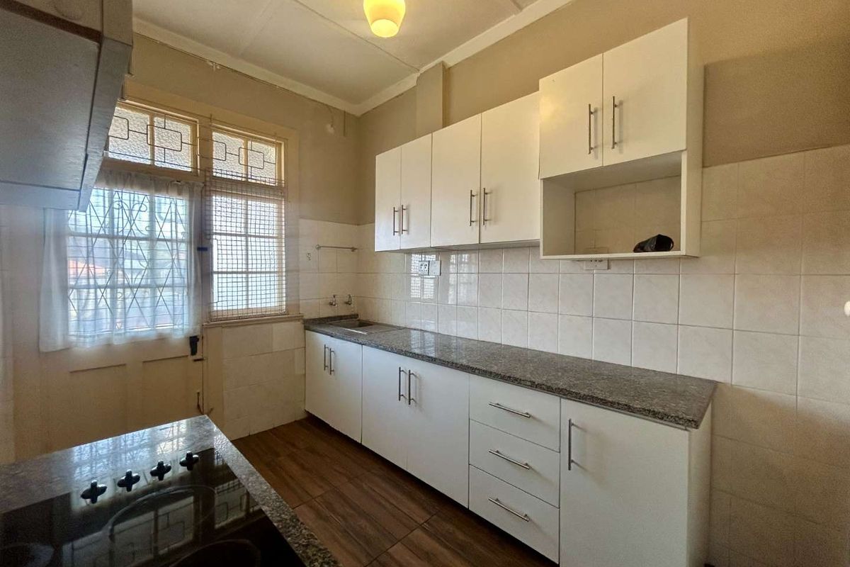 A functional kitchen featuring white built-in cabinetry, granite countertops, tiled backsplash, and a built-in hob, offering a clean and practical workspace.