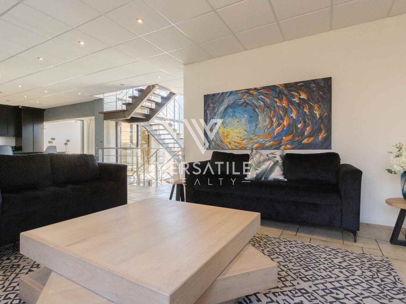 Spacious open-plan living area featuring a modern staircase, tiled flooring, and recessed lighting, seamlessly connecting to the kitchen space.