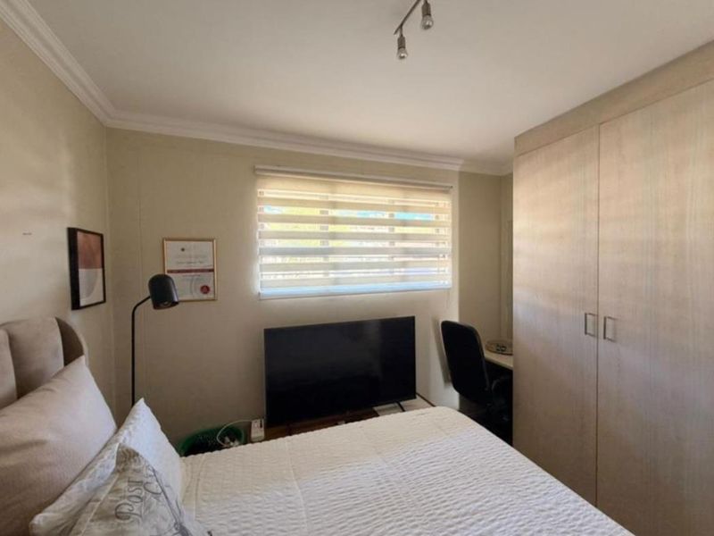 A well-maintained bedroom featuring neutral walls, built-in wardrobes, and modern roller blinds, providing a functional and comfortable living space.