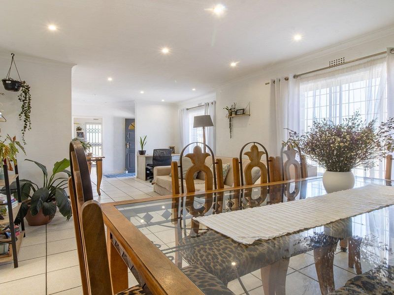 Spacious open-plan living and dining area featuring neutral tiled flooring, recessed downlighting, and large windows allowing for ample natural light.