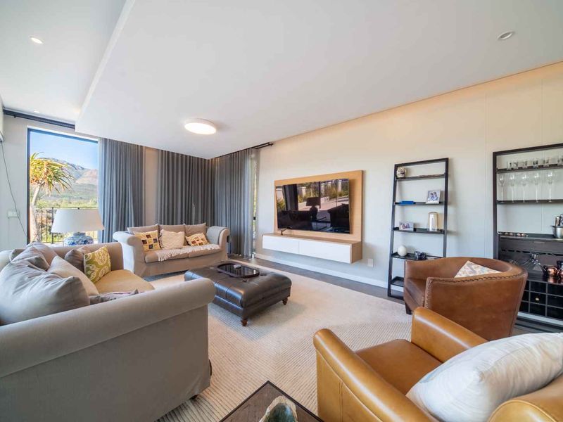Spacious, modern living room featuring a built-in media console, recessed ceiling lighting, and large sliding glass doors offering scenic views.