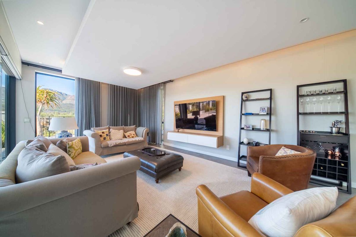 Spacious, modern living room featuring a built-in media console, recessed ceiling lighting, and large sliding glass doors offering scenic views.