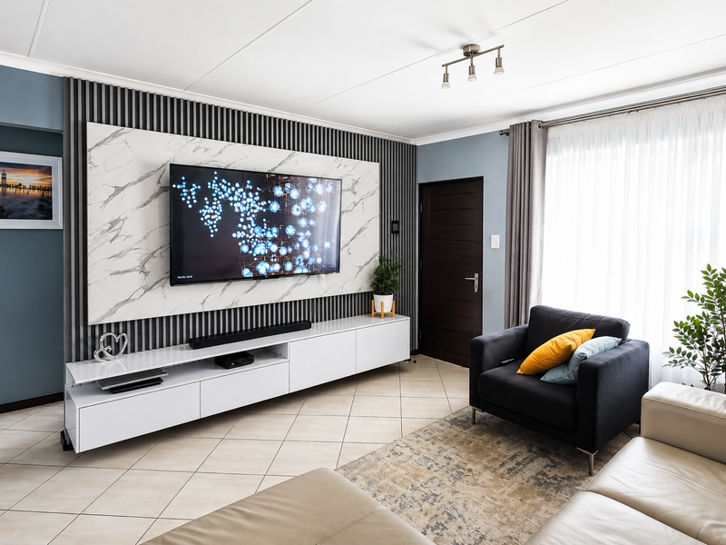 Modern living room featuring a stylish marble-look feature wall with integrated slatted paneling, built-in media cabinetry, and neutral tiled flooring.