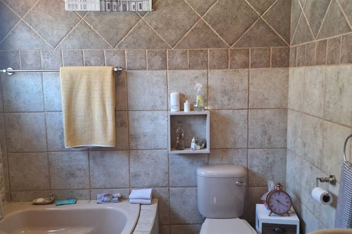 A bathroom featuring a corner bathtub, a standard toilet, and a vanity basin with tiled walls and flooring.