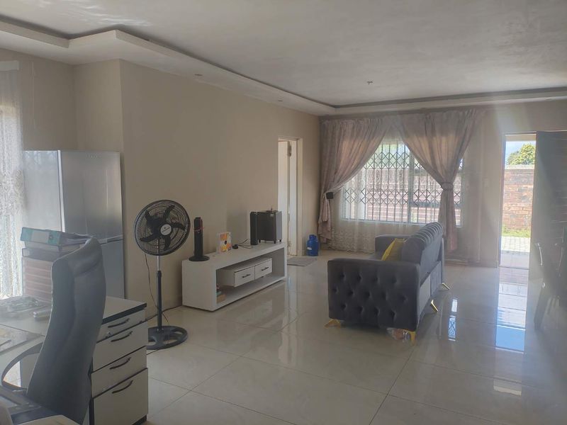Spacious living area featuring large format porcelain floor tiles, recessed ceiling lighting, and a sliding door providing access to the exterior.