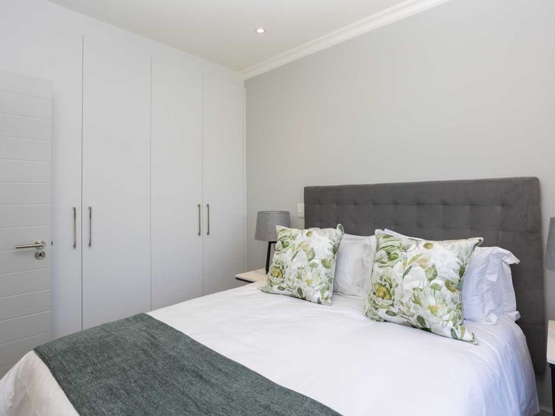A well-maintained bedroom featuring neutral walls, recessed downlighting, and ample built-in cupboard storage.