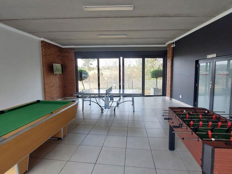 A spacious communal games room featuring tiled flooring, exposed brick accents, and large sliding glass doors leading to an outdoor area.