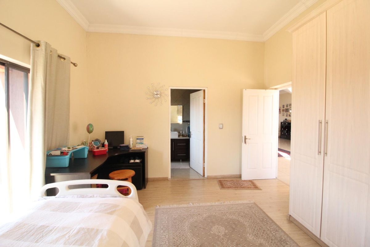 A spacious bedroom featuring built-in cupboards, laminate flooring, and an en-suite bathroom entrance.