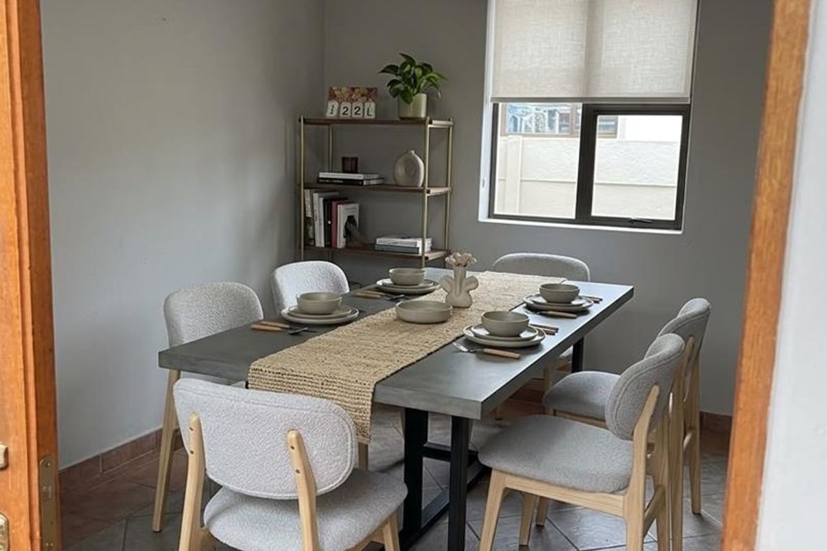A well-lit dining room featuring tiled flooring, a modern pendant light, and a window with a roller blind, providing a functional space for meals.