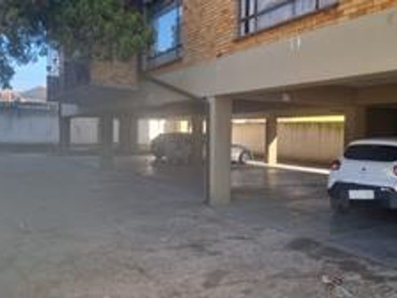 Covered parking area located beneath the apartment building, featuring concrete flooring and structural support pillars.