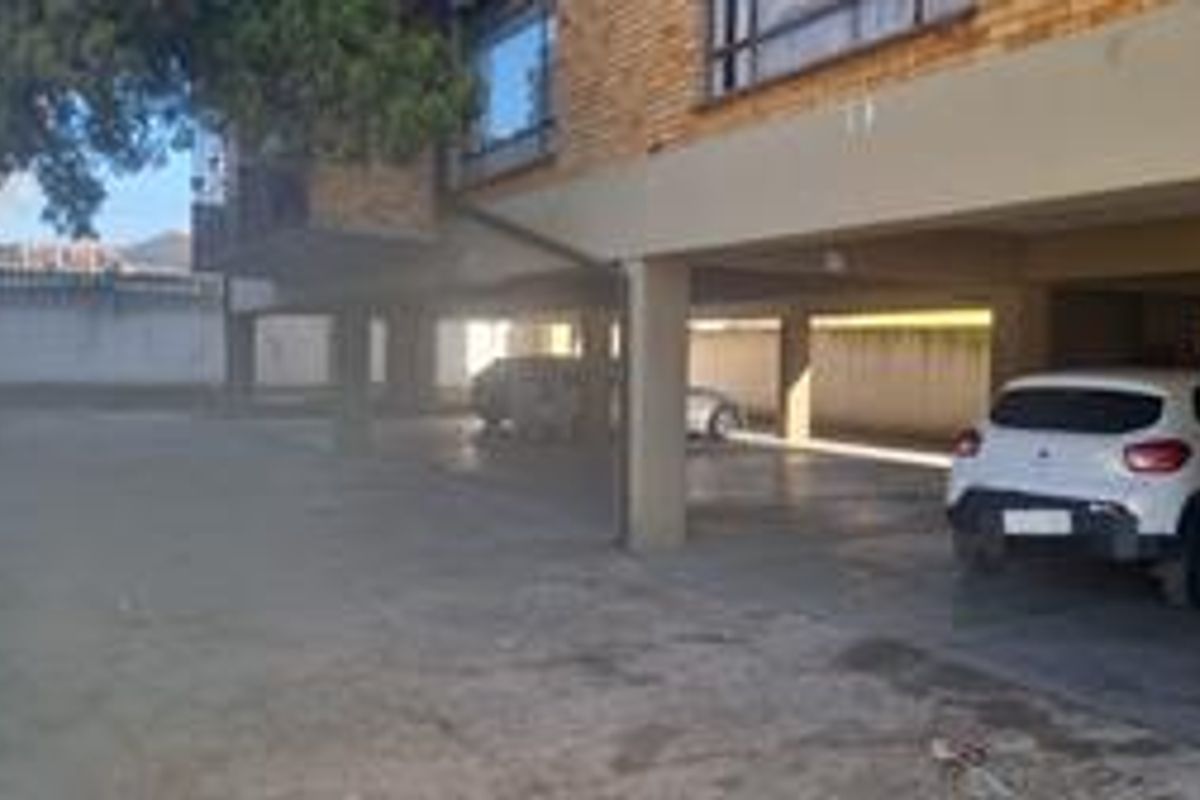 Covered parking area located beneath the apartment building, featuring concrete flooring and structural support pillars.