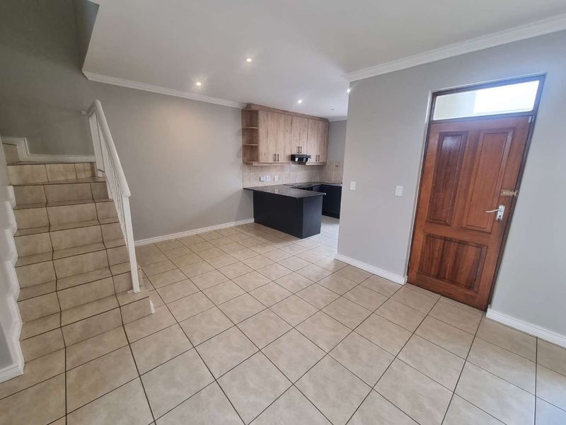 Open plan living area featuring tiled flooring, a staircase, and a modern kitchen with granite countertops and timber cabinetry.
