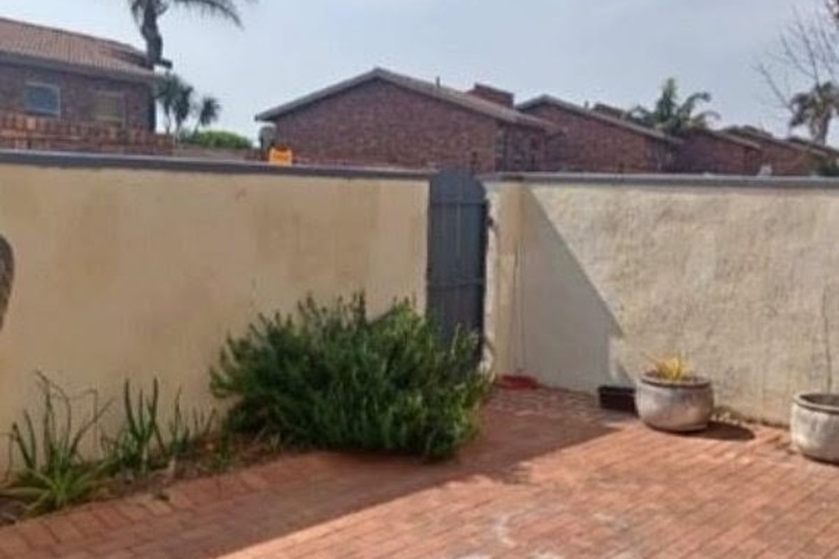 A private rear courtyard featuring brick paving, a secure pedestrian gate, and high boundary walls.