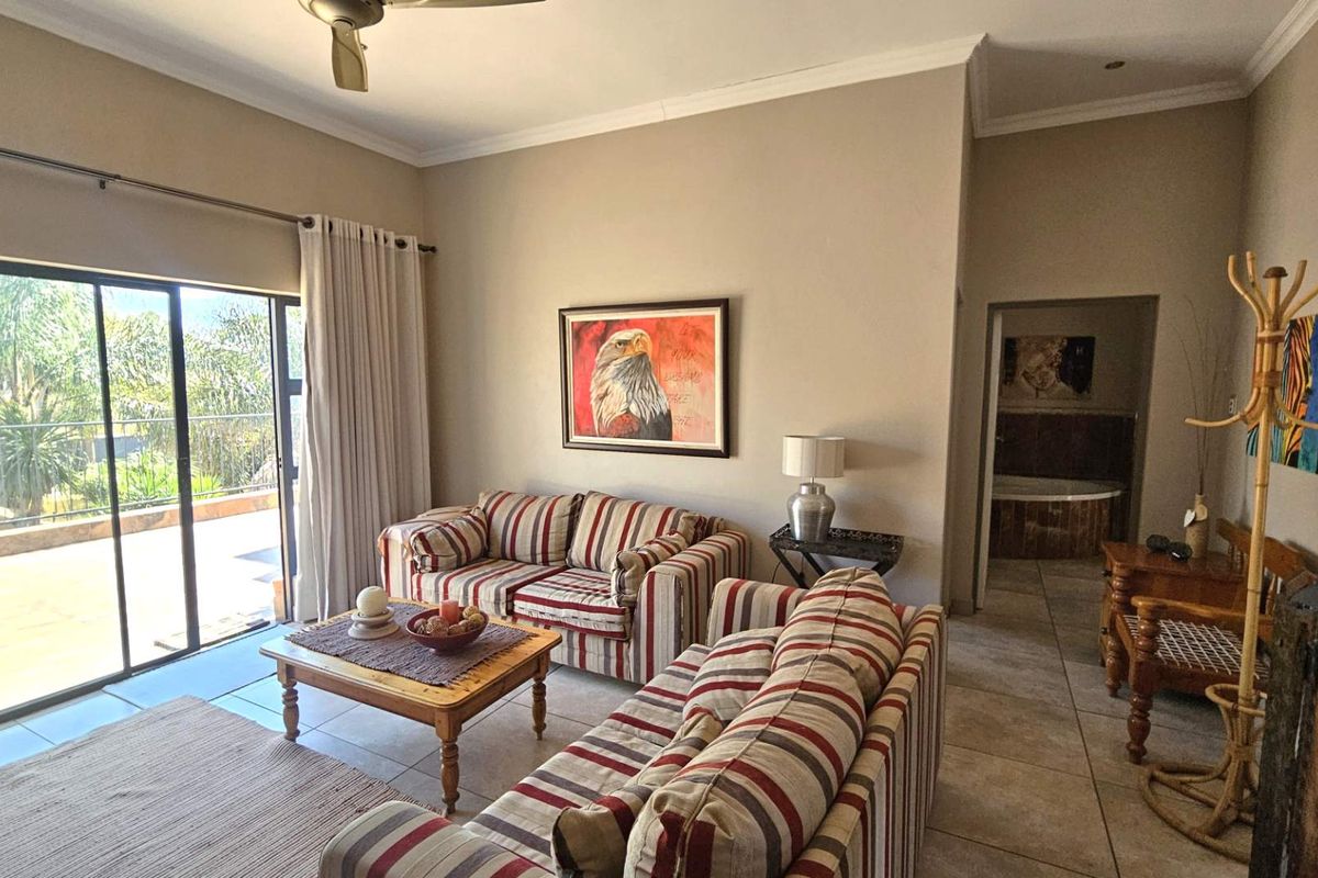 Spacious living room featuring tiled flooring, a ceiling fan, and large sliding glass doors providing access to an outdoor balcony area.
