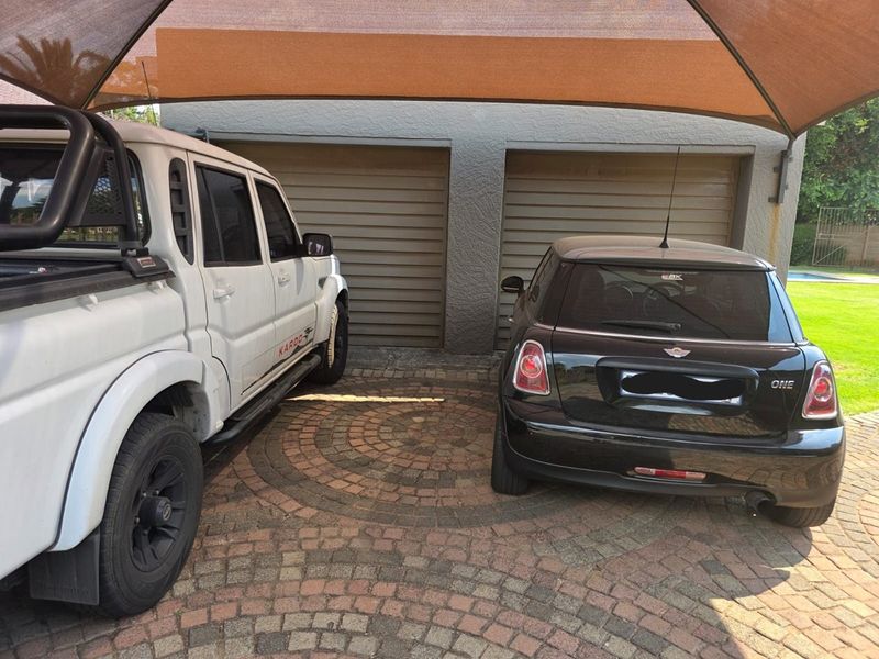 A double garage featuring a paved driveway and a protective shade sail covering the parking area.