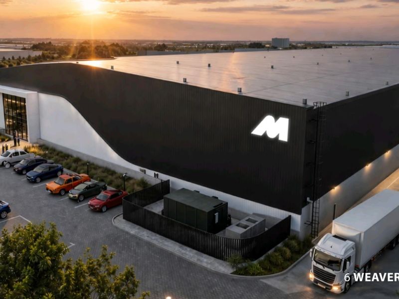 Aerial view of a modern industrial warehouse facility featuring large-scale cladding, dedicated parking areas, and efficient loading bay access at sunset.