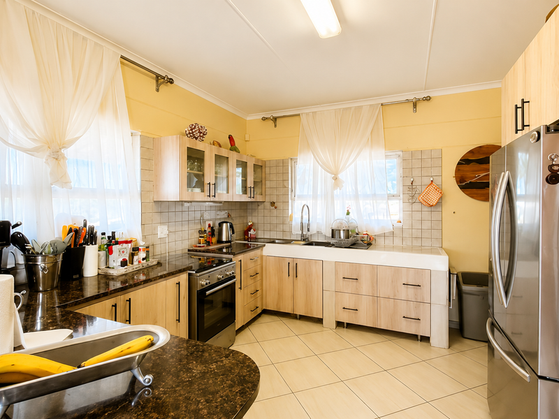 A functional kitchen featuring light wood cabinetry, granite countertops, a stainless steel oven, and a double basin sink with tiled backsplash.