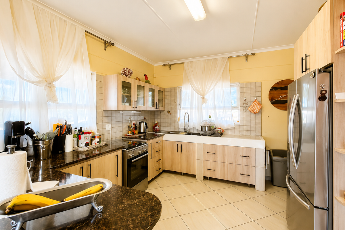 A functional kitchen featuring light wood cabinetry, granite countertops, a stainless steel oven, and a double basin sink with tiled backsplash.