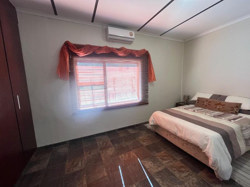 A bedroom featuring tiled flooring, a built-in wardrobe, and a wall-mounted split-system air conditioner.