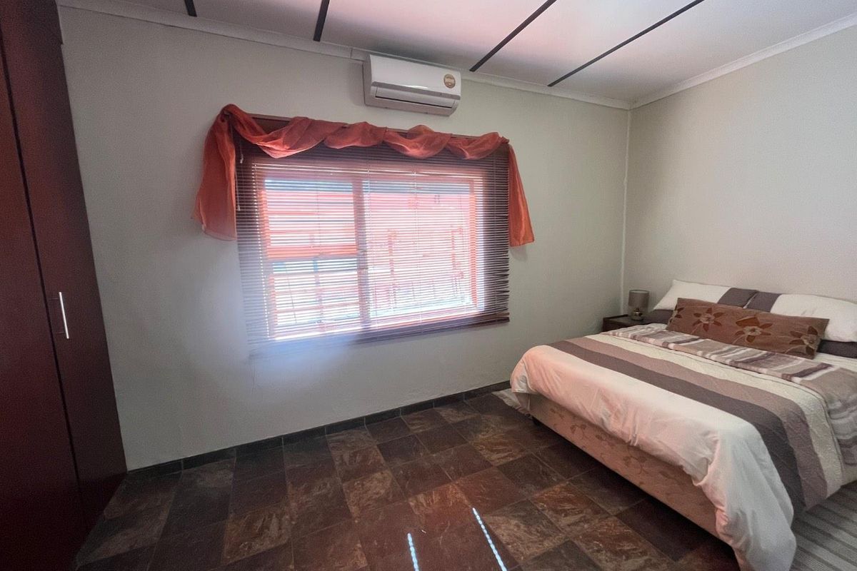 A bedroom featuring tiled flooring, a built-in wardrobe, and a wall-mounted split-system air conditioner.