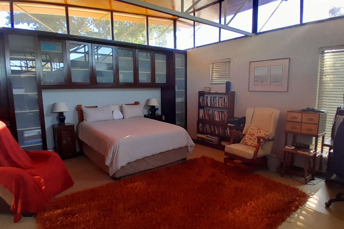 Spacious bedroom featuring high-level clerestory windows, built-in dark wood cabinetry, and neutral wall finishes.
