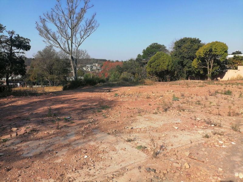 A vacant residential plot featuring cleared ground and established trees, offering a blank canvas for new construction.
