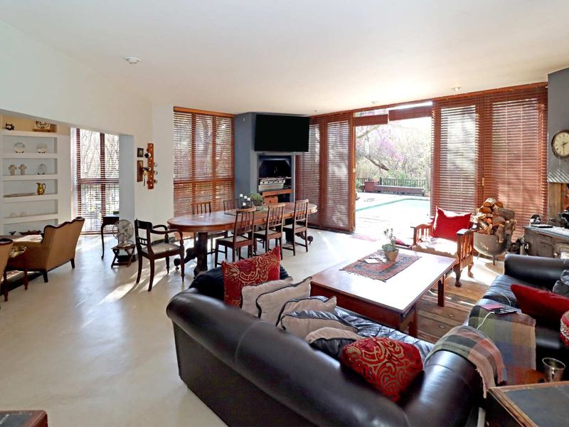 Spacious open-plan living and dining area featuring built-in shelving, a wood-burning stove, and large sliding doors opening to the outdoor pool area.