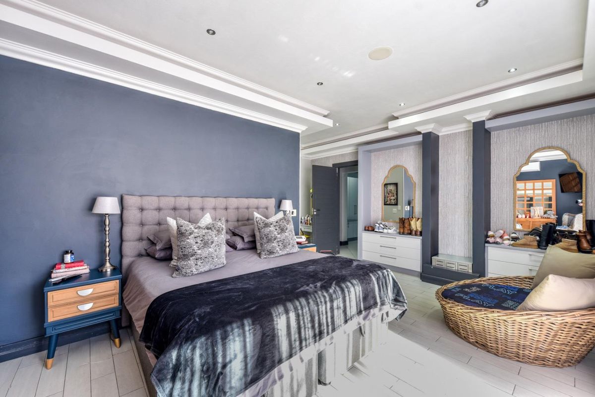 Spacious primary bedroom featuring built-in cabinetry, recessed ceiling details with crown molding, and integrated downlighting.