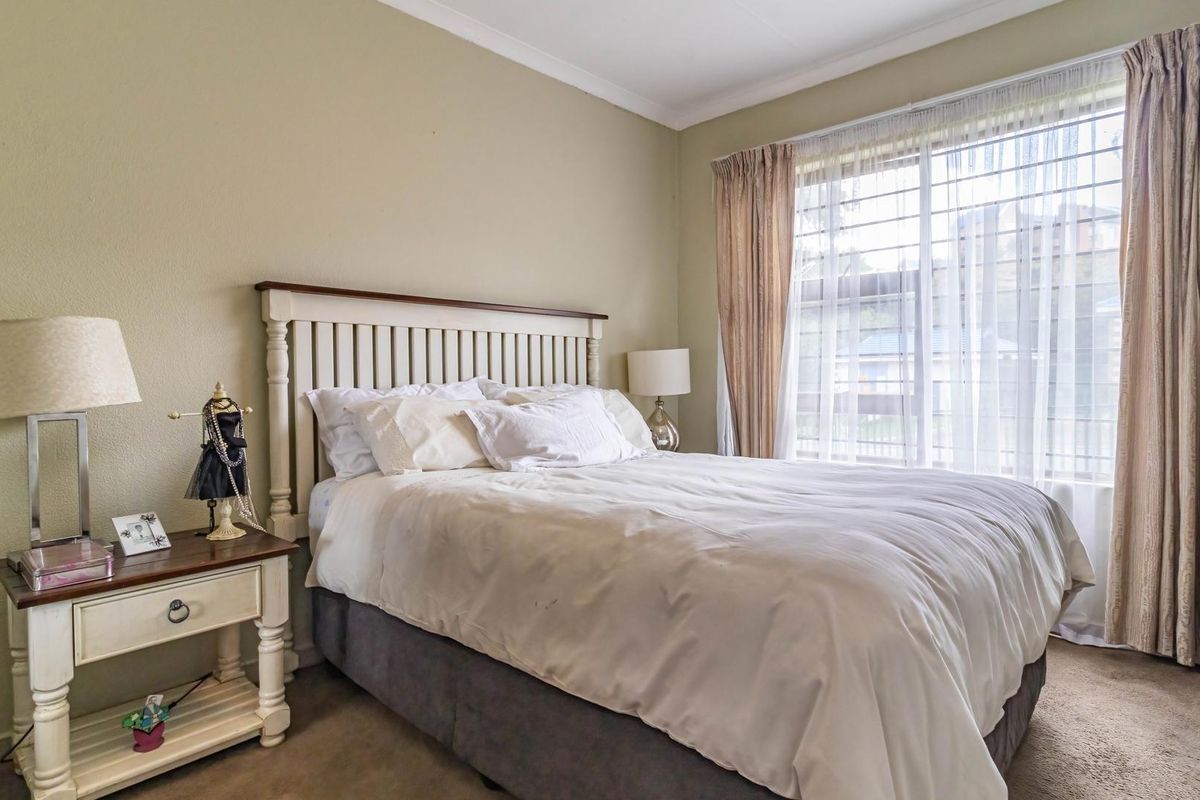 A carpeted bedroom featuring a window with security bars and decorative coving.