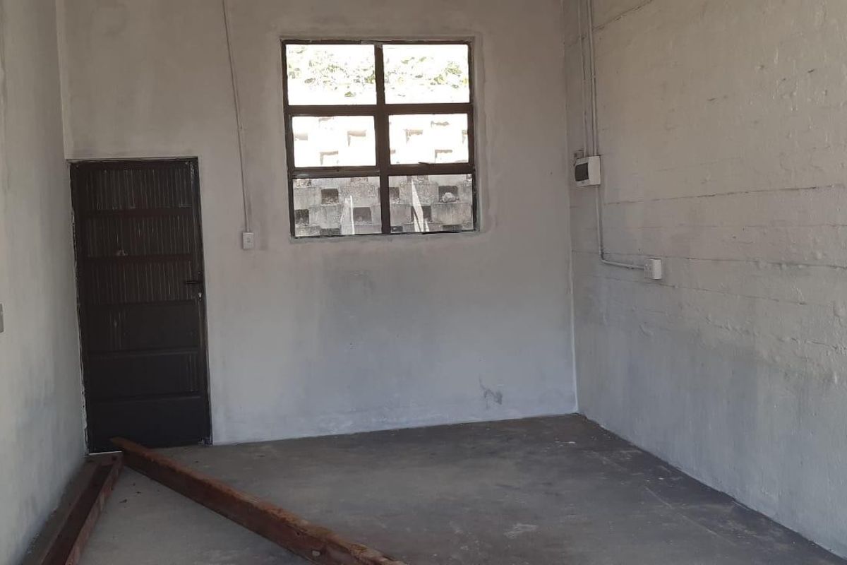 An industrial utility space featuring painted brick walls, concrete flooring, and exposed electrical conduit, suitable for storage or workshop use.