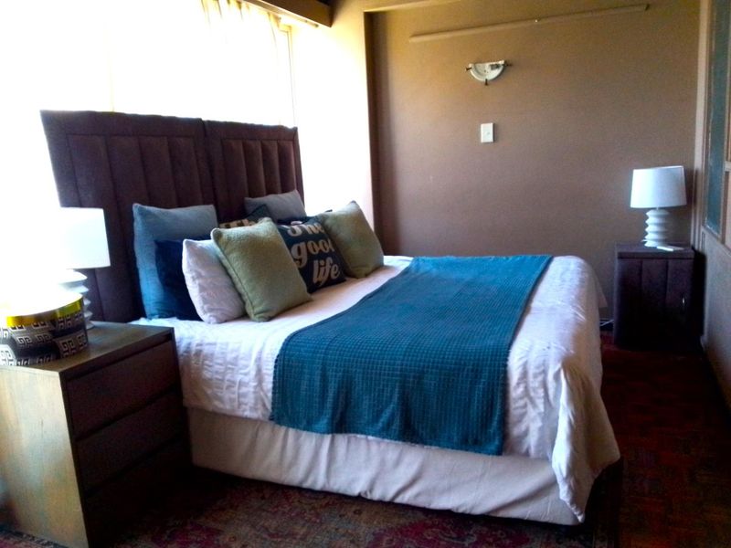A bedroom featuring a large window, wall-mounted lighting, and neutral wall finishes.
