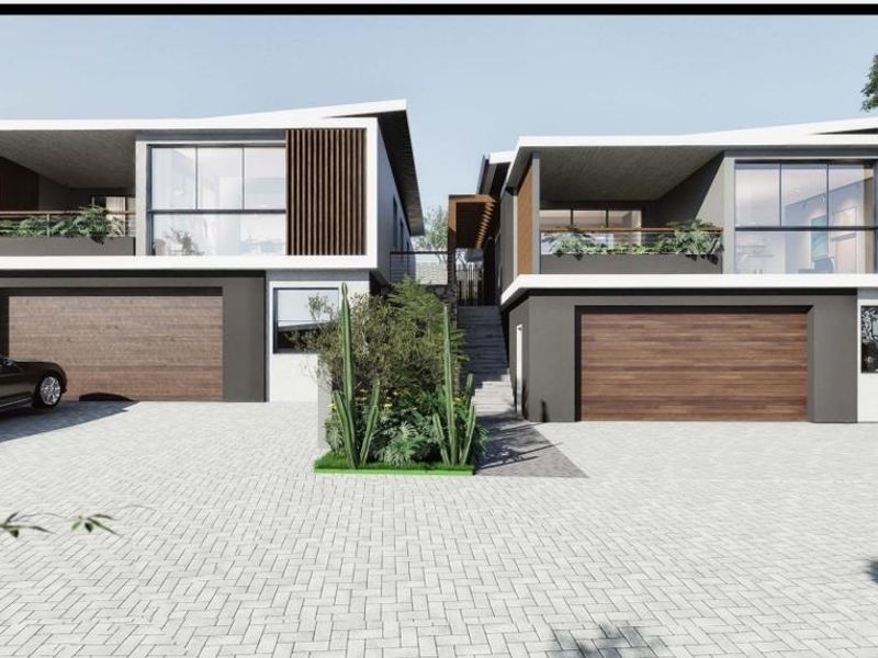 Modern double-story residential facade featuring timber accents, large glass windows, paved driveway, and integrated double garages.
