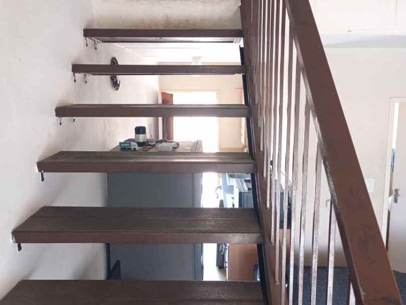 Interior view of a staircase with a metal balustrade leading to a mezzanine level in an apartment.