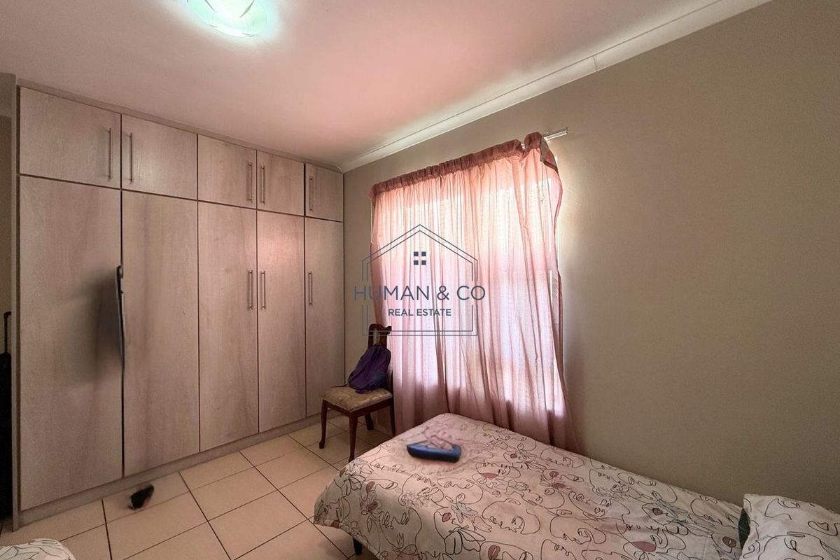 A bedroom featuring built-in floor-to-ceiling cabinetry and tiled flooring, providing functional storage space.