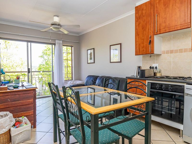 Open-plan living and kitchen area featuring tiled floors, built-in cabinetry, and a sliding door leading to a balcony.