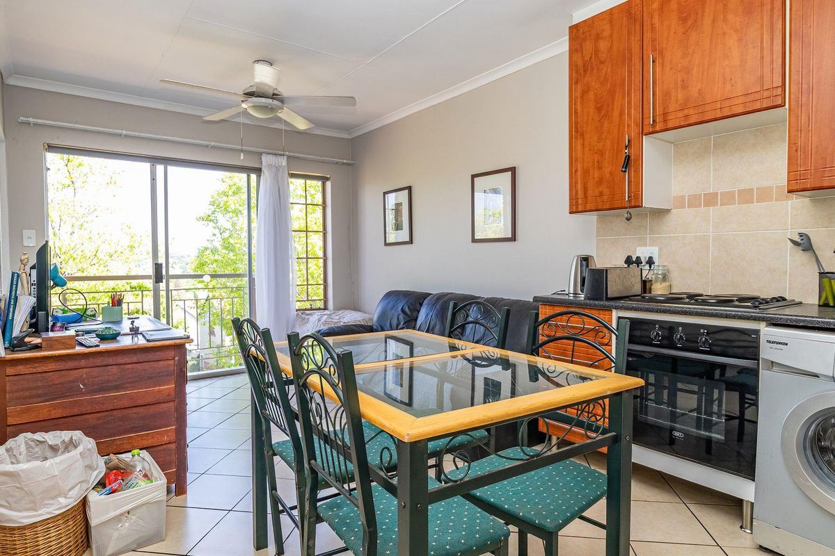 Open-plan living and kitchen area featuring tiled floors, built-in cabinetry, and a sliding door leading to a balcony.