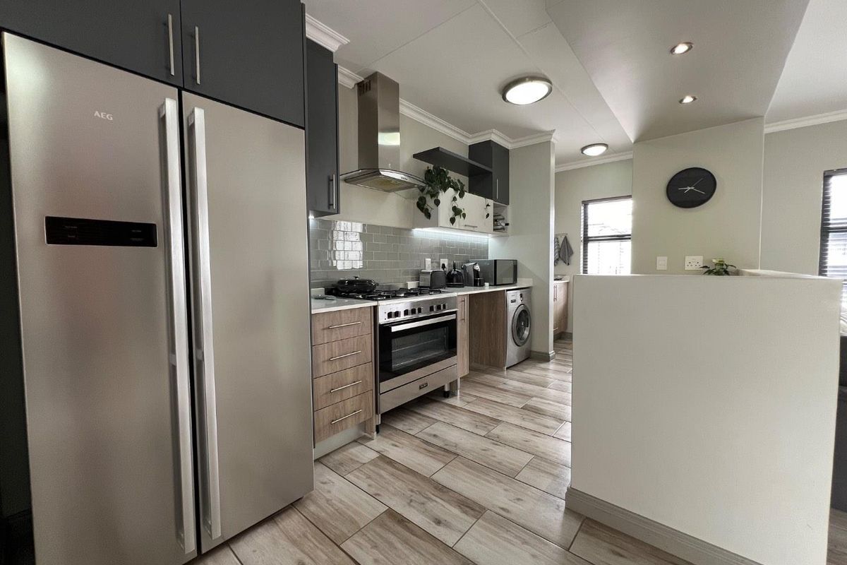 Modern kitchen featuring wood-tone and dark cabinetry, stainless steel appliances, subway tile backsplash, and contemporary tiled flooring with recessed lighting.