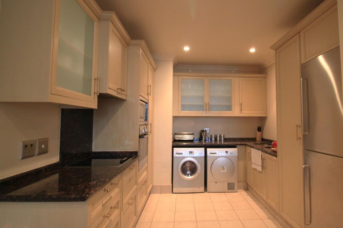 A well-appointed kitchen featuring neutral cabinetry, granite countertops, integrated oven, and dedicated space for laundry appliances.