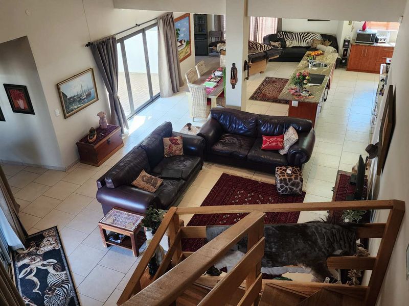 Spacious open-plan living area featuring a kitchen island, tiled flooring, and double-volume ceilings with direct access to the patio through sliding glass doors.
