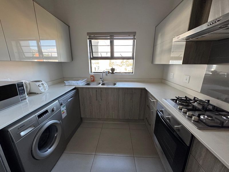 Modern kitchen featuring sleek cabinetry, stone countertops, integrated gas hob, oven, extractor fan, and tiled flooring with a functional layout.
