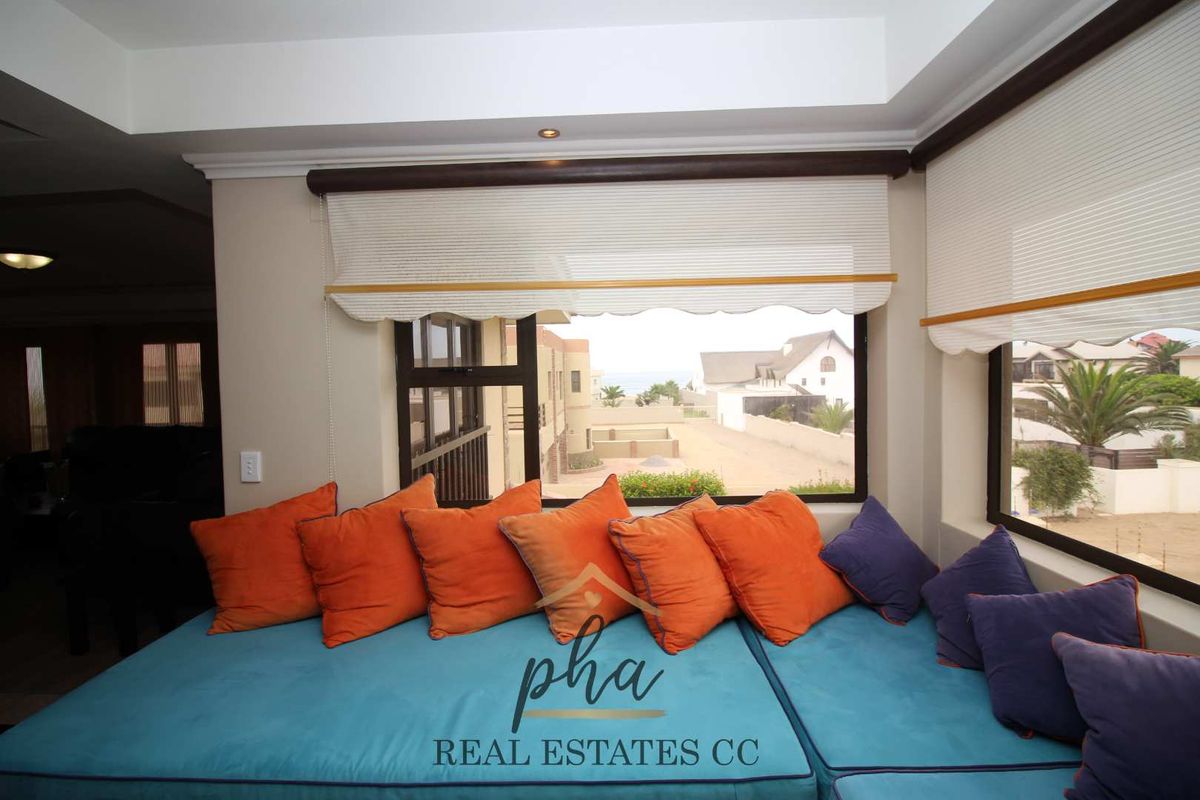 A cozy living area featuring large windows with built-in blinds, offering a pleasant view of the surrounding neighborhood and distant sea.