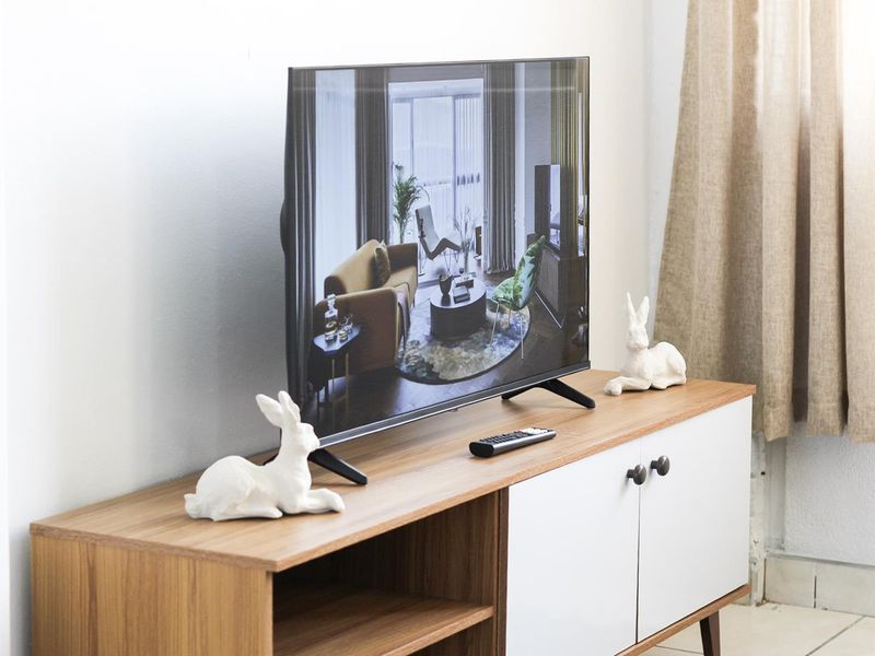 A close-up view of a television set placed on a modern wooden media console in a living area.