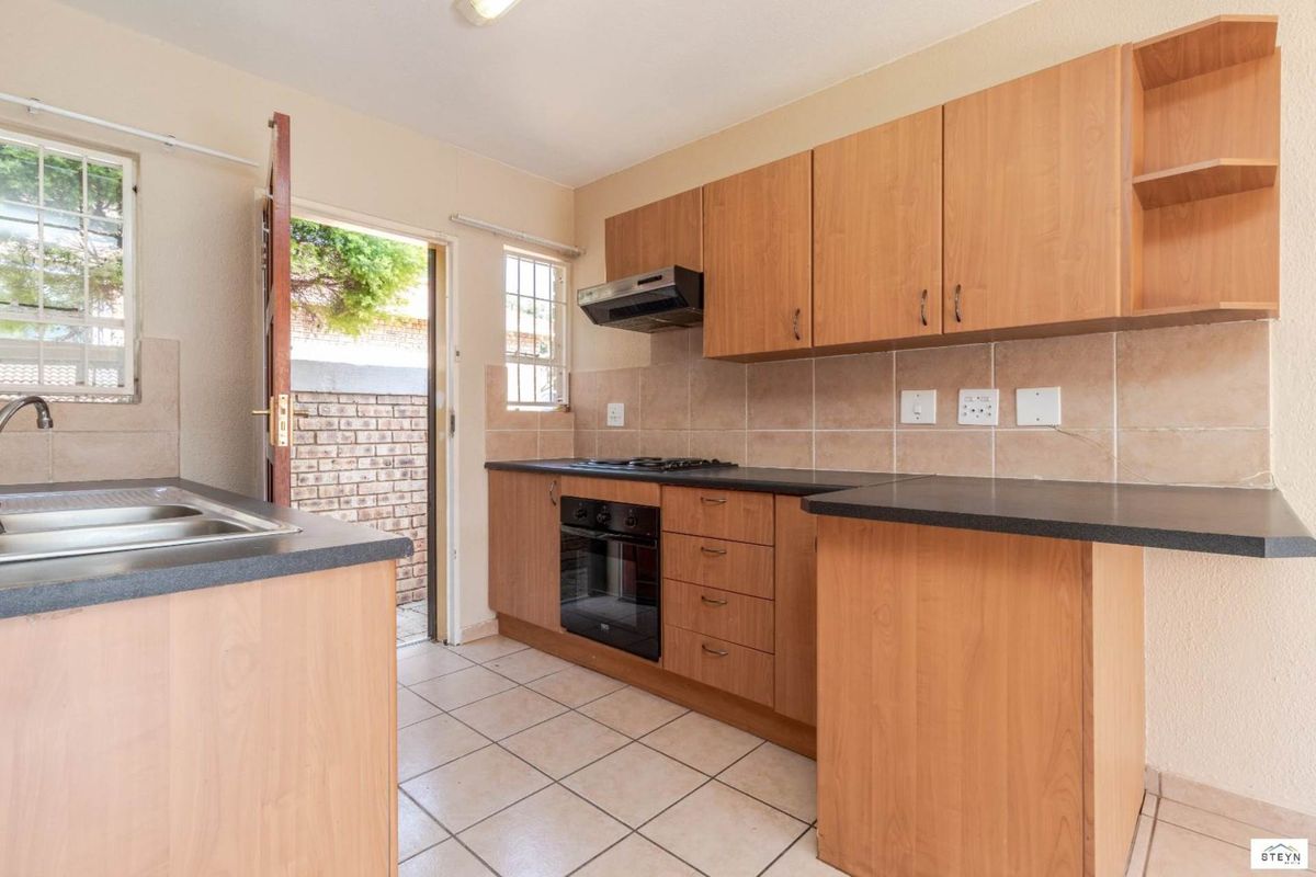 Functional kitchen featuring laminate cabinetry, built-in oven, gas hob, and direct access to an exterior courtyard area.