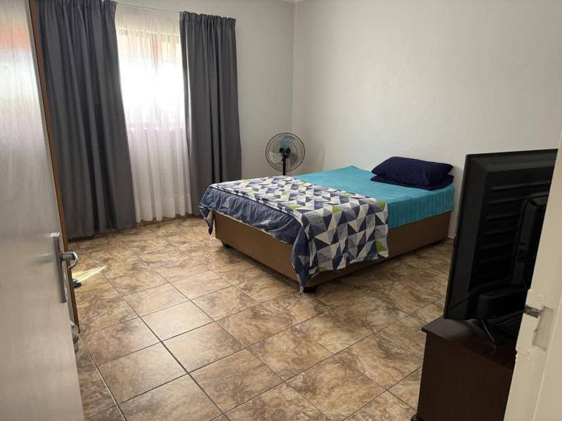 A functional bedroom featuring tiled flooring and neutral wall finishes, providing a clean and simple space.