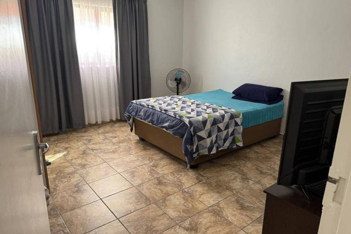A functional bedroom featuring tiled flooring and neutral wall finishes, providing a clean and simple space.